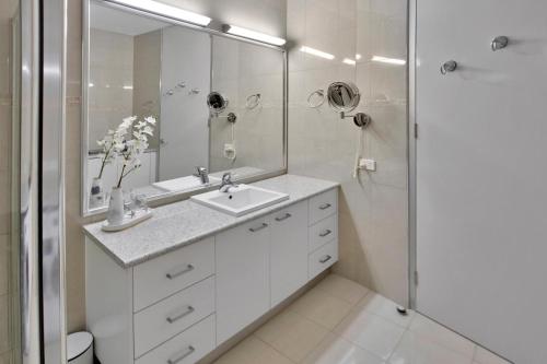 La salle de bains blanche est pourvue d'un lavabo et d'une douche. dans l'établissement Harbour Views, à Lakes Entrance