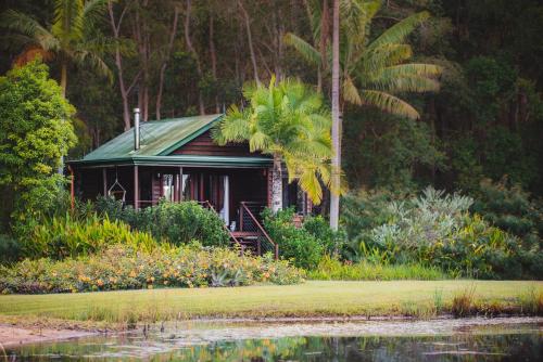 a house that has a tree in front of it at Lake Weyba Cottages Noosa in Peregian Beach