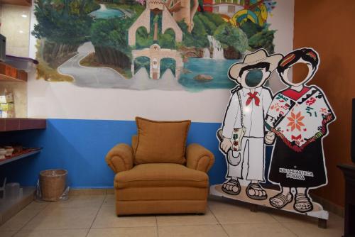 a room with a chair and a painting of a couple at Kali Huasteca Posada in Ciudad Valles