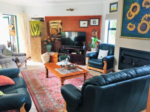 a living room with black leather furniture and a tv at The Sun Catcher Bed & Breakfast in Struisbaai