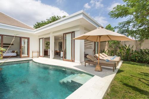 Villa con piscina y sombrilla en Gajah Villas Bali by Nagisa Bali, en Seminyak