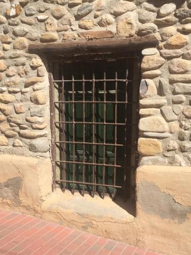 a window with bars on the side of a stone building at casa de piedra.The stone house in Turre