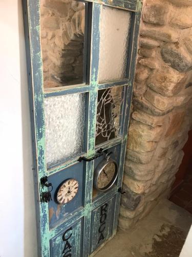 an old door with clocks on it next to a stone wall at casa de piedra.The stone house in Turre