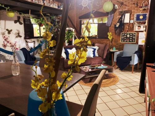 ein Wohnzimmer mit einem Sofa und einem Tisch mit gelben Blumen in der Unterkunft Casa de Mirtes in Fernando de Noronha