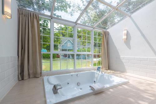 een groot wit bad in een kamer met een raam bij Peggy's Cove Resort in Chao Lao Beach