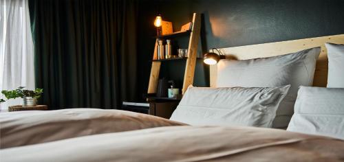 a bedroom with a bed with white pillows and a shelf at Urban Nature St Peter-Ording in Sankt Peter-Ording