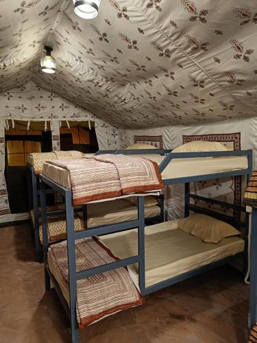 a room with three bunk beds and a ceiling with flowers at Jaseelo Camps near Tehri Lake in Chamba