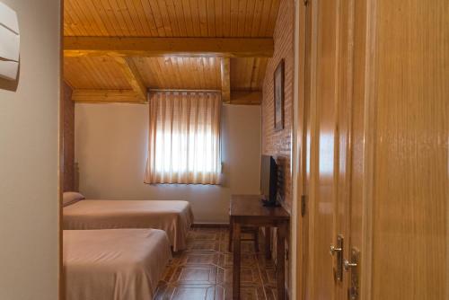 a small room with two beds and a window at Hotel-Restaurante La Sima in Castillo de Garcimuñoz