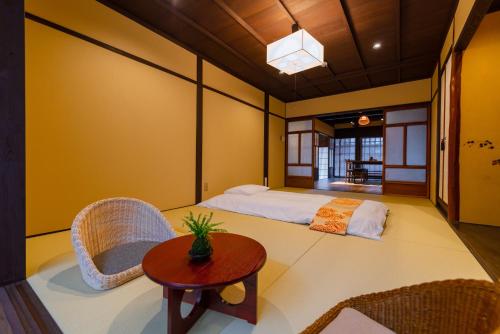 a bedroom with a bed and chairs and a table at Kyotofish·Masuya*Reformed Machiya*Gardenview Bath in Kyoto