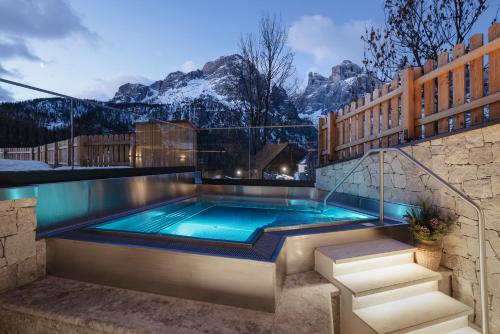 a swimming pool with mountains in the background at Garnì La Dorada in Colfosco
