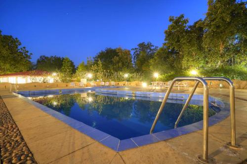 a swimming pool at night with lights at Bundela Bandhavgarh by Octave in Mānpur