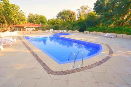 a large swimming pool with blue water in a yard at Bundela Bandhavgarh by Octave in Mānpur