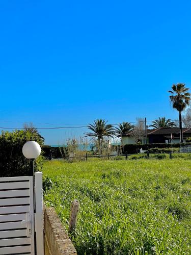 a white fence in a field with palm trees at Oasi del Mare… in Ortona