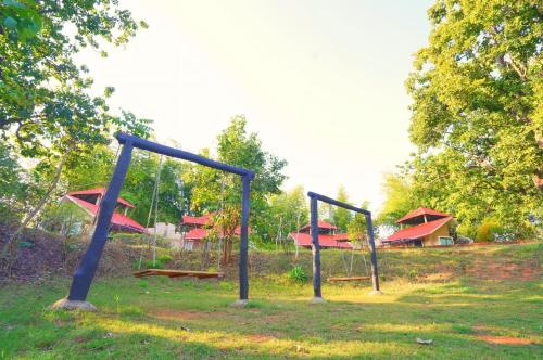 a playground with two swings in a field at Bundela Bandhavgarh by Octave in Mānpur