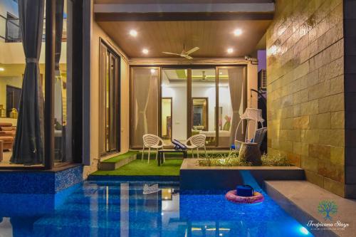 a house with a pool in front of a house at Ignite Villa By Tropicana Stays in Lonavala