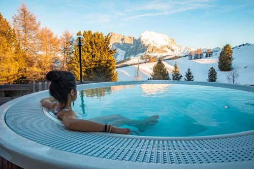Paradiso Pure Living Vegetarian-Vegan Hotel في ألب دي سوزي: امرأة جالسة في حوض استحمام ساخن في الجبال