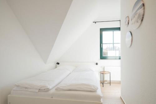 a white bedroom with a bed and a window at Ferienwohnung Lee West 2 3 in Dierhagen