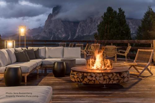 een vuurplaats op een terras met een bank en stoelen bij Paradiso Pure Living Vegetarian-Vegan Hotel in Alpe di Siusi