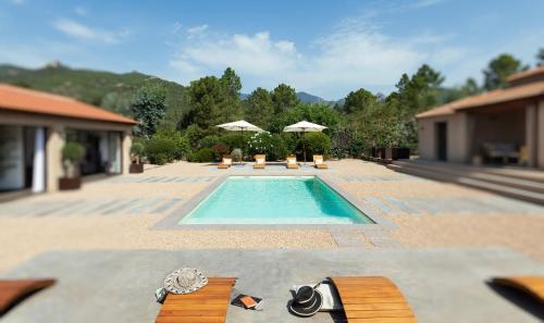 een zwembad met banken en parasols in een achtertuin bij **** VILLA CASA DI FIUMU **** in Porto-Vecchio