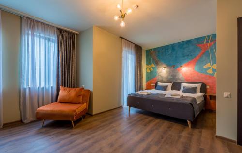 a bedroom with a bed and a chair and a painting at Tourfa in Tbilisi City