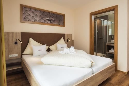 a bedroom with a large bed with white sheets at Gabriela Appartements INKLUSIVE SUPER SOMMER CARD in Serfaus