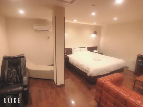 a bedroom with a bed and a chair and a couch at HOTEL 555 Air in Higashine