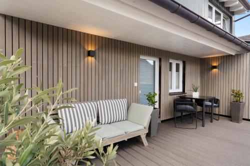 a patio with a couch and a table on a deck at Second Home - Ferienwohnungen Fischbach in Friedrichshafen
