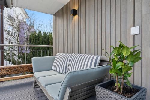 a blue couch on a porch with a potted plant at Second Home - Ferienwohnungen Fischbach in Friedrichshafen