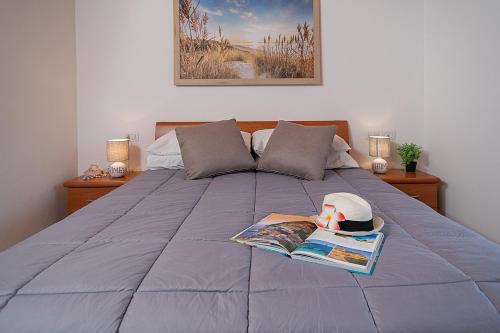 un letto con un libro e un cappello e una rivista di APARTMENT L'ARCHETTO - Regarda Travel a Lazise