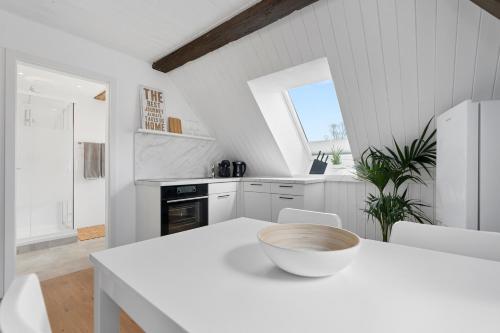 a white kitchen with a table and a bowl on it at Second Home - Ferienwohnungen Fischbach in Friedrichshafen