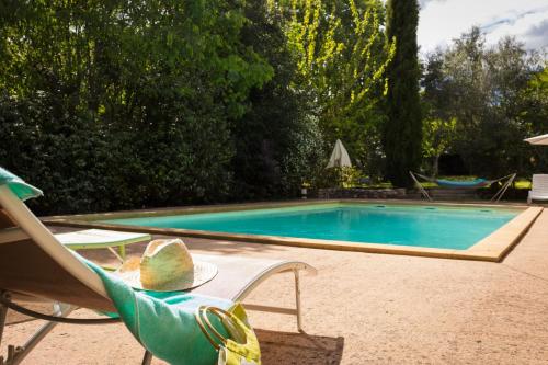 - une piscine avec une chaise, une table et un siège sidx dans l'établissement Le Mas des Sages, à Aubussargues