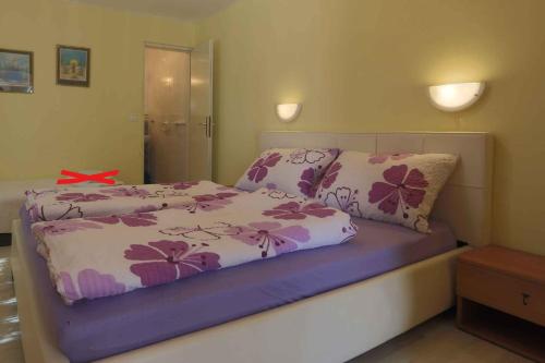 een slaapkamer met een bed met paarse en roze bloemen bij Apartment Silo 36 in Šilo