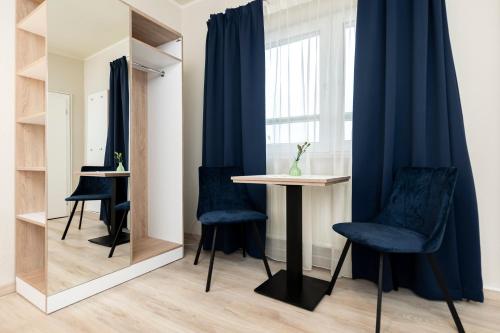 a room with blue chairs and a table and a window at Aparthotel Stralsund Studios und Apartments in Stralsund