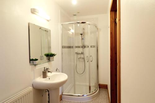 a white bathroom with a shower and a sink at Acarsaid B&B in Lybster