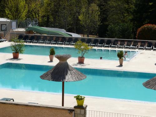 a swimming pool with an umbrella and chairs at Hôtel Les Vignes in Chassiers