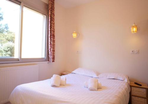 a bedroom with two beds with white sheets and a window at Hôtel Restaurant Le Sainte Marguerite in Pornichet