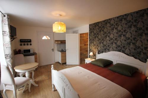 a bedroom with a bed and a table and a chair at Les Petits Jardins de Cissé Chambre de Charme in Cissé