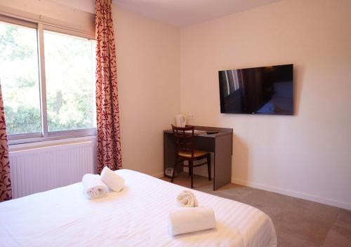 a bedroom with a bed and a desk and a television at Hôtel Restaurant Le Sainte Marguerite in Pornichet