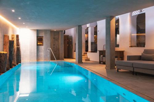 a large swimming pool in a room with a couch at Himmlhof in Sankt Anton am Arlberg