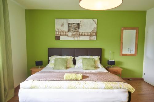 a bedroom with a large bed with green walls at Gästezimmer Victoria in Linsberg