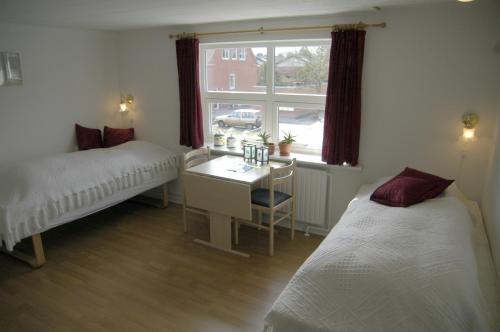 a bedroom with two beds and a desk and a window at Nr. Nebel Overnatning Hostel in Nørre Nebel