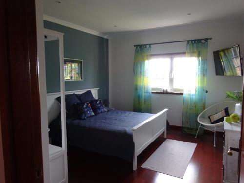 a bedroom with a bed with blue sheets and a window at Ferienhaus Casa do mar mit seitlichem Meerblick in Vila Chã