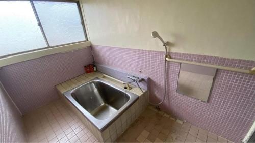 um lavatório numa casa de banho em azulejos cor-de-rosa com uma janela em BRIDGE Share House em Shimonoseki