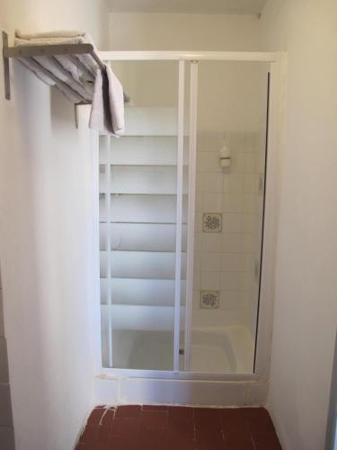 une douche avec une porte vitrée dans une salle de bain dans l'établissement Le Guintrand, à Bédoin