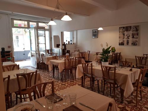 uma sala de jantar cheia de mesas e cadeiras com toalhas de mesa brancas em Le Guintrand em Bédoin