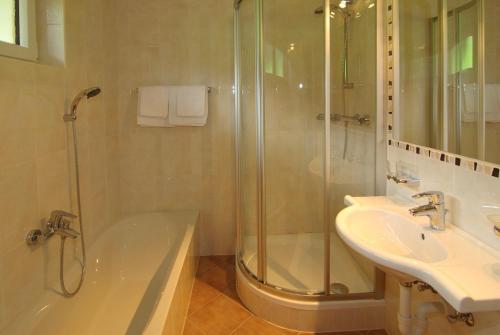 uma casa de banho com um chuveiro, uma banheira e um lavatório. em Pension Schusterhof em Itter
