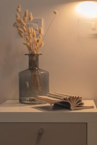 a book and a vase with flowers on a table at I GELSI B&B in Copertino
