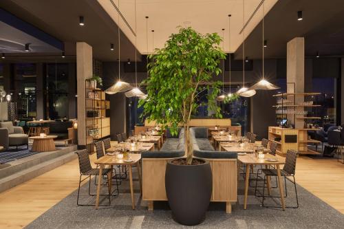 a restaurant with tables and a potted tree in the middle at Century City Hotel Bridgewater in Cape Town