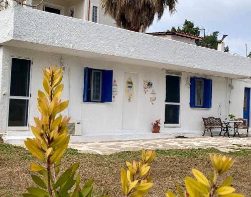 Casa blanca con ventanas azules y mesa en Relaxation, Nature and Sea Near the Airport! en Loútsa