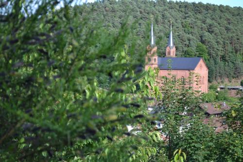 un grand bâtiment en briques avec une église avec une cloche dans l'établissement Hotel Am Hirschhorn - Wellness - Spa - and more, à Wilgartswiesen